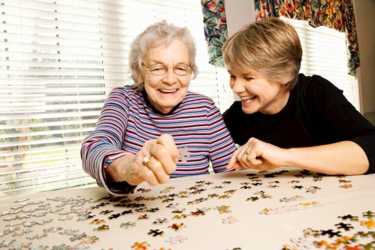 Elderly woman and younger person putting a puzzle together