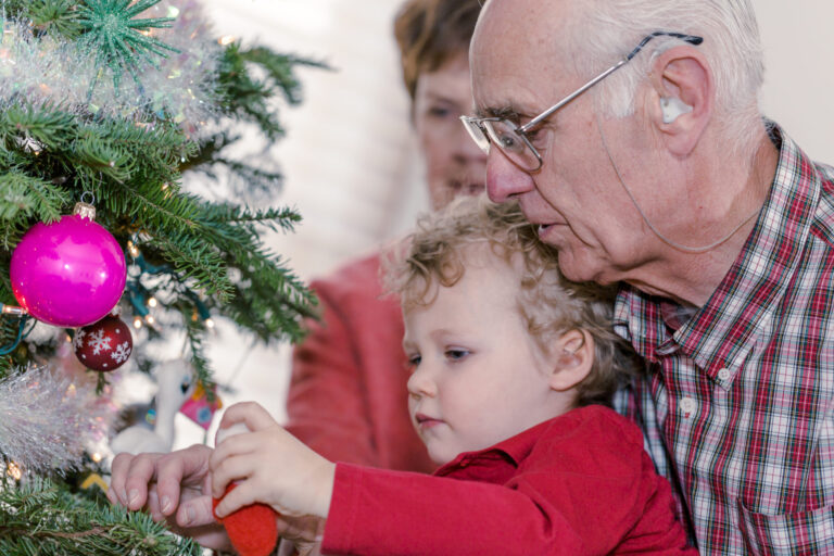 Grandfather lifting grandson to decorate Christmas tree