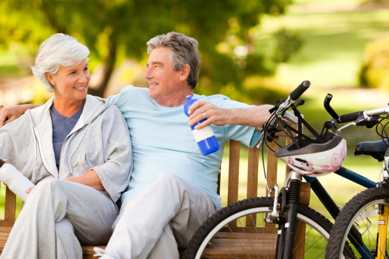 Elderly couple sitting on a bench with their bikes